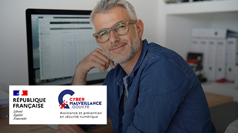 visuel pour Cybermailveillance : Homme souriant près de son ordinateur